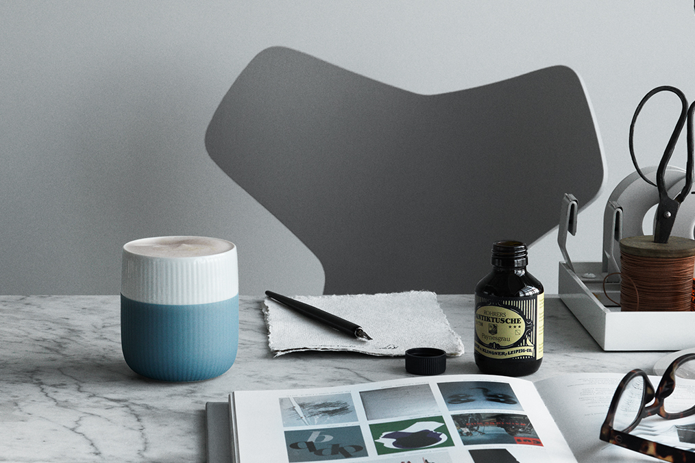 The Fluted Contrast Mug in Light Blue on a desk filled with books, pens and magazines